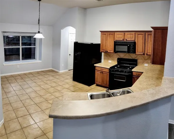 a kitchen with stainless steel appliances kitchen island wooden cabinets a stove a sink and a refrigerator