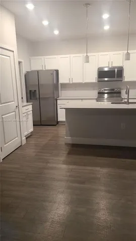 a view of a kitchen with stainless steel appliances granite countertop a stove and a refrigerator