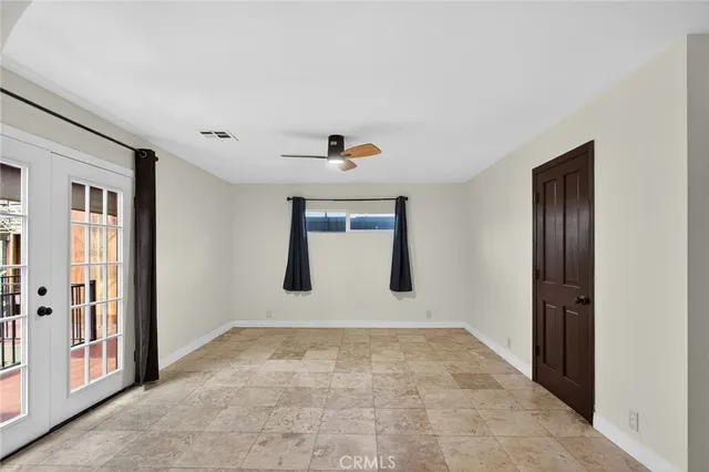 a view of an empty room with wooden floor ceiling fan and window