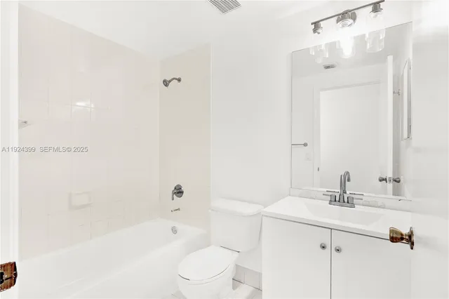 a bathroom with a bathtub shower sink vanity mirror and toilet