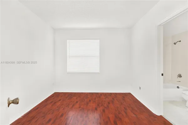 a view of a room that has wooden floor and has more cabinets