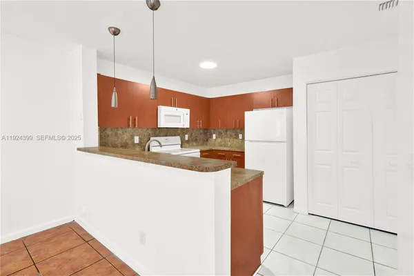 a kitchen with stainless steel appliances granite countertop a refrigerator a oven and a sink with granite countertops