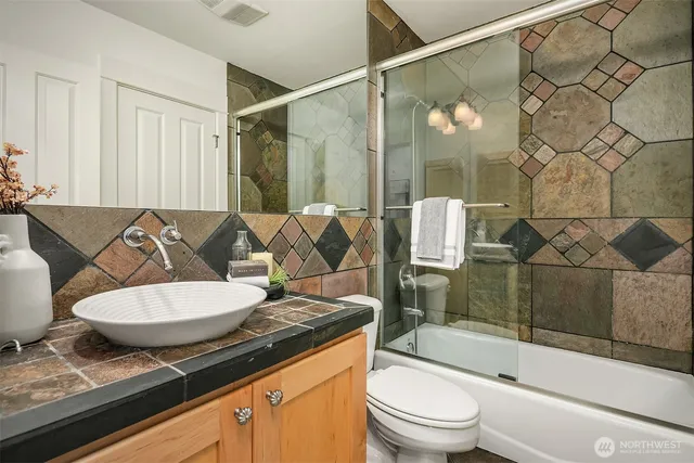 a bathroom with a granite countertop sink toilet a mirror and shower