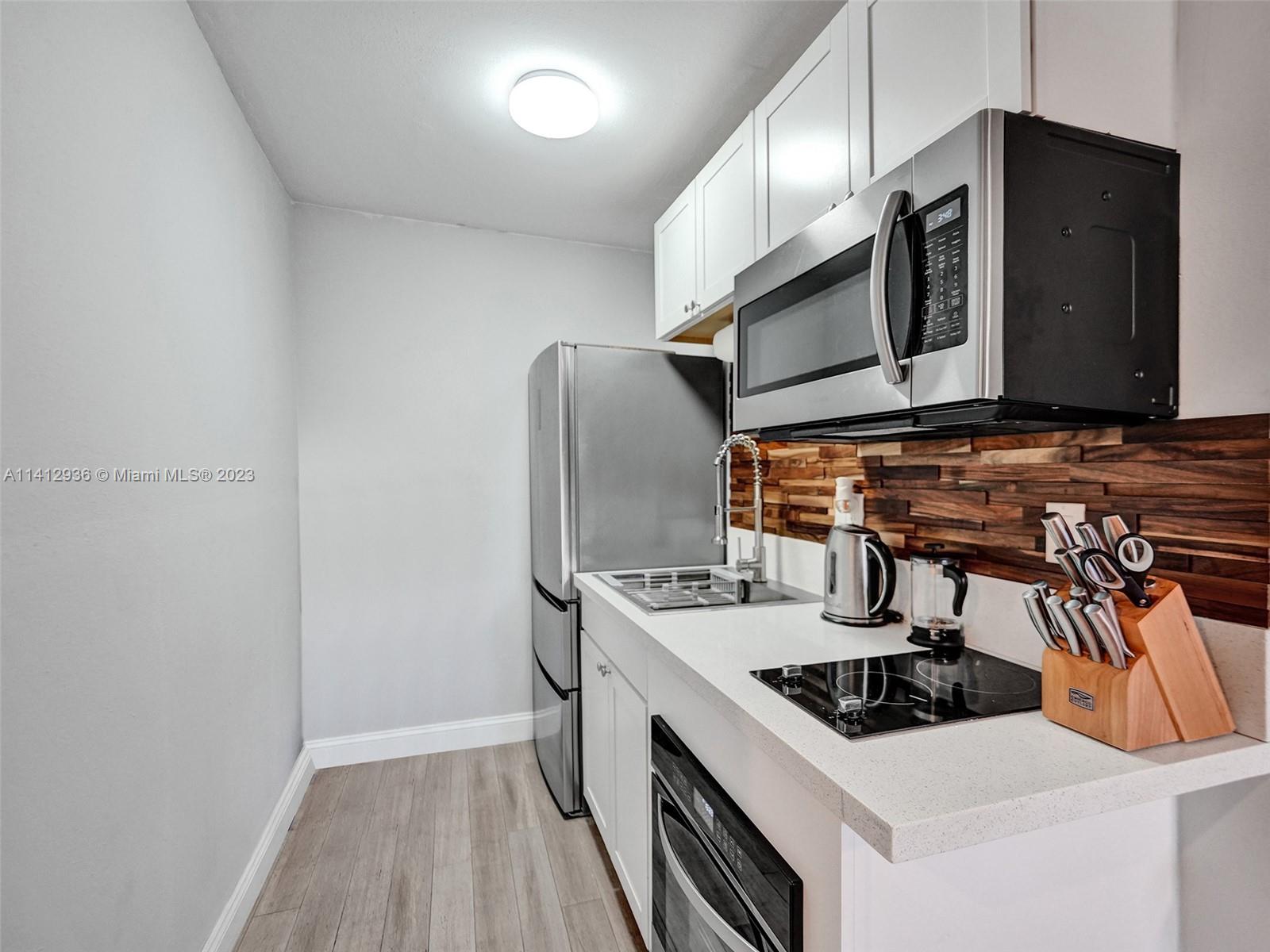 2500 Northeast 19th Street Pompano Beach, FL 33062 - Photo 32 of 51 a kitchen with stainless steel appliances a sink a stove and a refrigerator with wooden floor