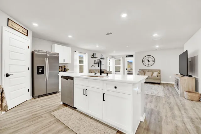 a large white kitchen with a refrigerator a stove a sink and a cabinets