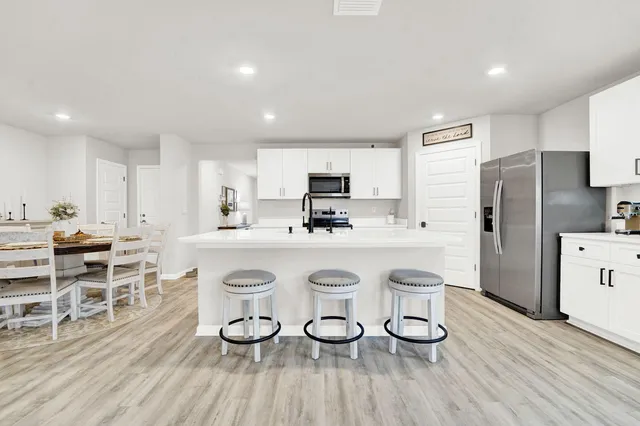a kitchen with stainless steel appliances a table and chairs in it