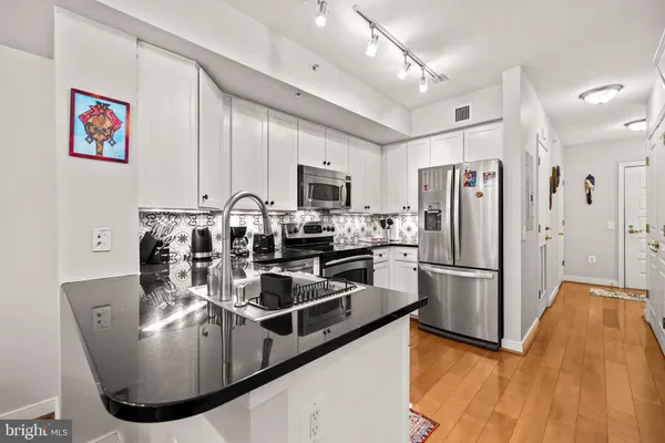 a kitchen with cabinets stainless steel appliances and wooden floor