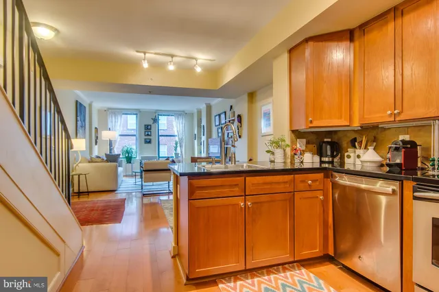 a kitchen with stainless steel appliances granite countertop a refrigerator a sink dishwasher and wooden cabinets with wooden floor