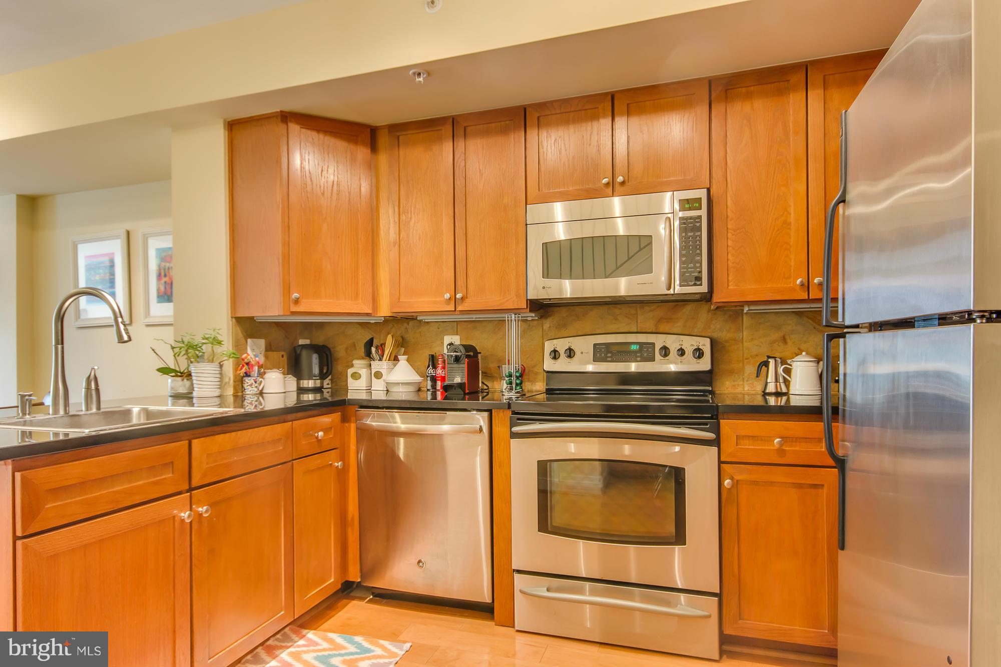 631 D Street Northwest, Unit 845 Washington, DC 20004 - Photo 8 of 30 a kitchen with stainless steel appliances granite countertop a stove a sink and white cabinets