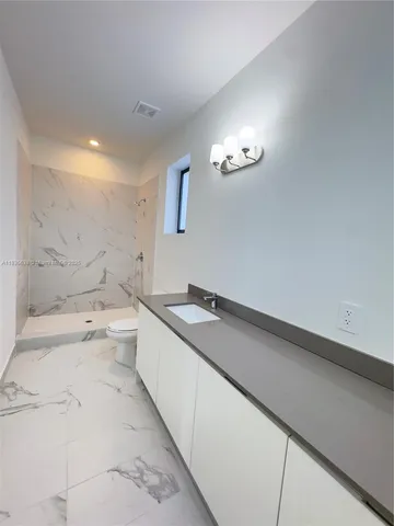 a bathroom with a granite countertop sink a toilet and bathtub