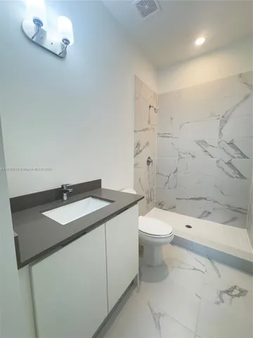 a bathroom with a granite countertop sink a toilet and a shower