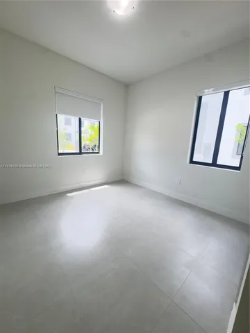 an empty room with windows and ceiling fan