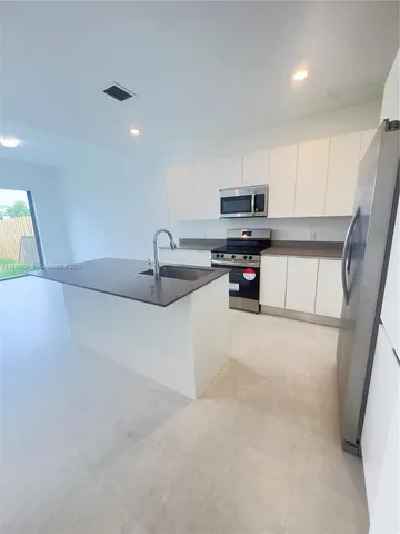 a kitchen with kitchen island a sink stainless steel appliances and a counter top