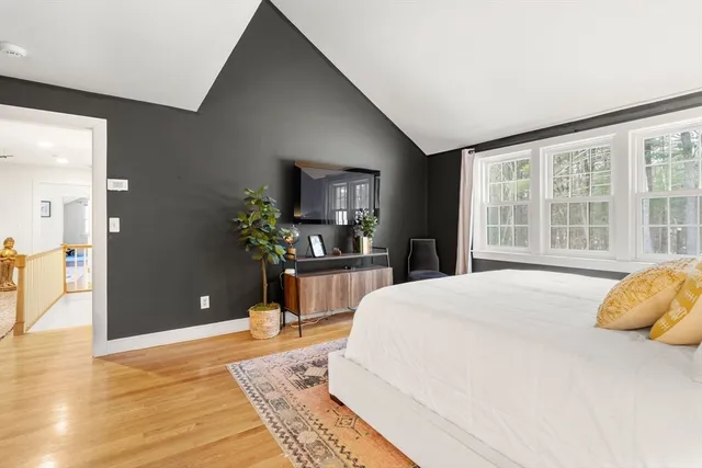 a bedroom with a bed dresser and a large window
