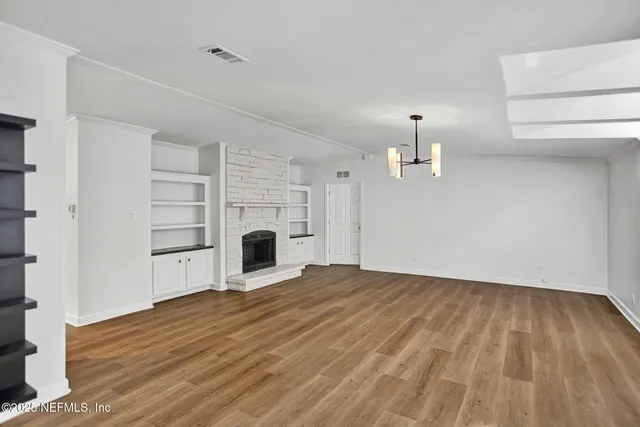 a view of empty room with wooden floor and fireplace