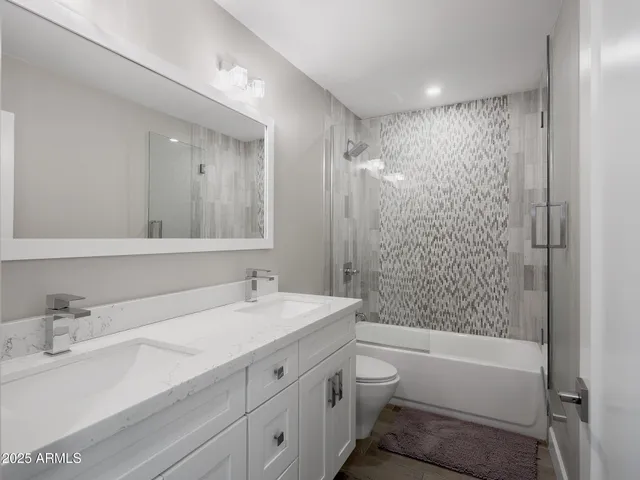a bathroom with a bathtub shower sink vanity mirror and toilet