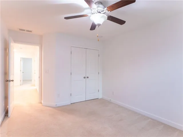 an empty room with closet and a chandelier fan