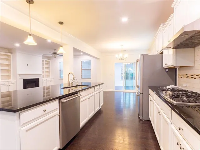 a kitchen with granite countertop a sink cabinets stainless steel appliances and a counter top space