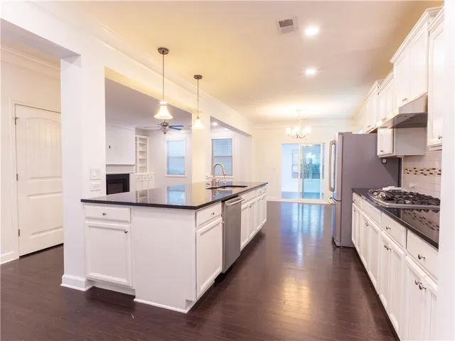 a view of an empty room with a kitchen chandelier fan and a kitchen view