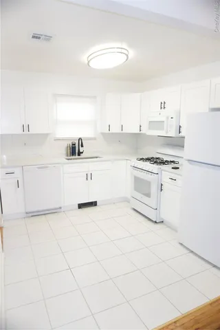 a kitchen with granite countertop white cabinets and white appliances