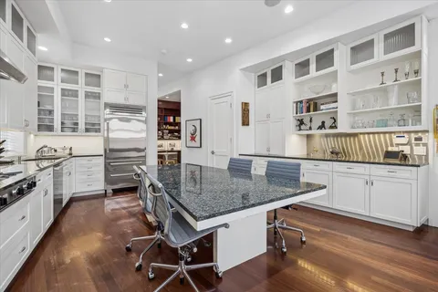 a kitchen with stainless steel appliances granite countertop a stove top oven a sink a dining table and chairs