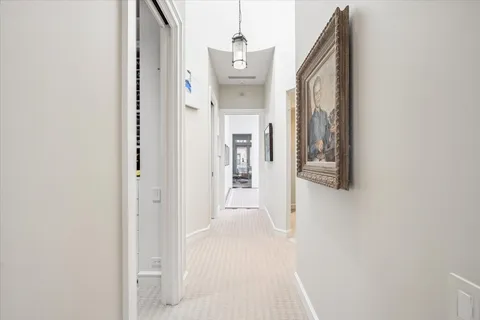 a view of a hallway with wooden floor and a bathroom
