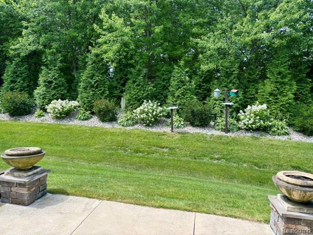 1876 Genoa Circle Howell, MI 48843 - Photo 33 of 36 Expansive green lawn with mature trees, established shrubbery, and perennial plantings