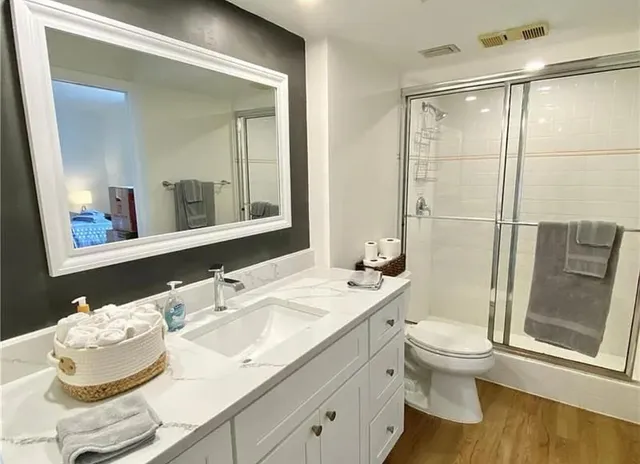 a bathroom with a granite countertop sink toilet a mirror and shower
