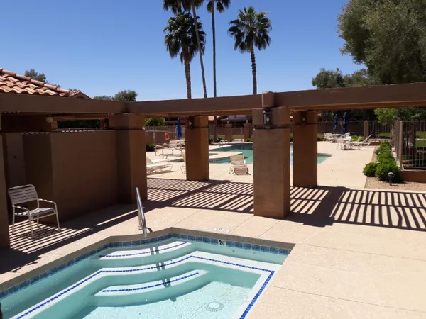 a view of a swimming pool with a lawn chairs under an umbrella