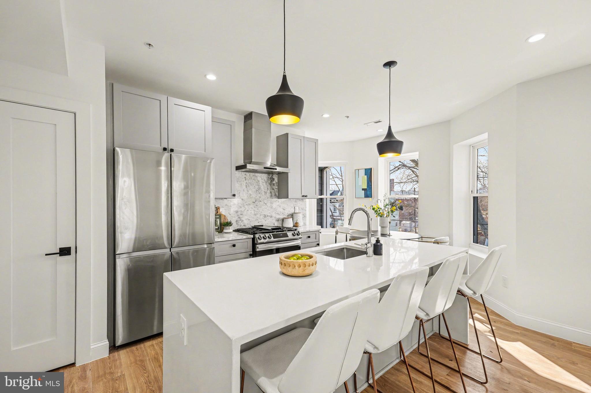 842 Madison Street Northwest, Unit 2 Washington, DC 20011 - Photo 5 of 27 a kitchen with stainless steel appliances kitchen island granite countertop a refrigerator a stove a kitchen island with a dining table and chairs