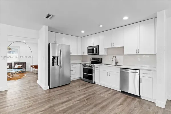 a kitchen with stainless steel appliances granite countertop a refrigerator a stove top oven a sink and dishwasher with wooden floor