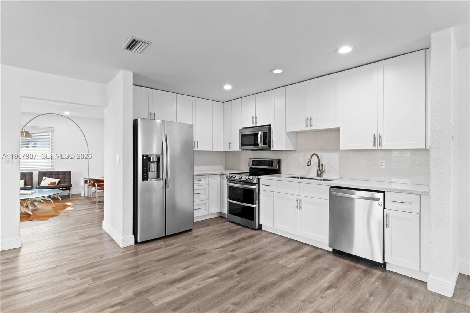 a kitchen with stainless steel appliances granite countertop a refrigerator a stove top oven a sink and dishwasher with wooden floor