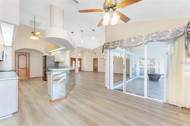 a view of an empty room with wooden floor and a ceiling fan