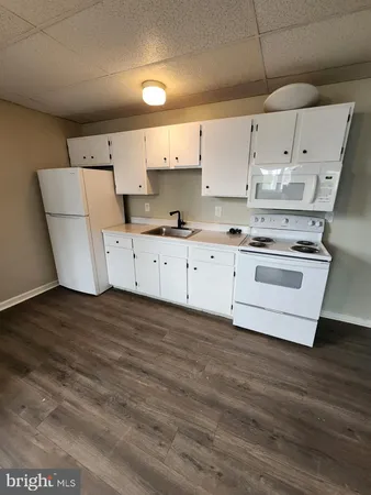 a kitchen with cabinets wooden floor and stainless steel appliances
