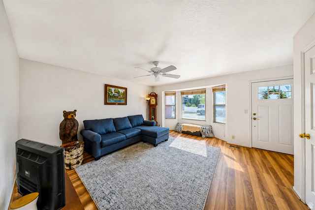 9990 Albury Road Sandy, UT 84092 - Photo 6 of 36 Bright living area featuring wood-finish flooring, a ceiling fan with light, and a prominent bay window