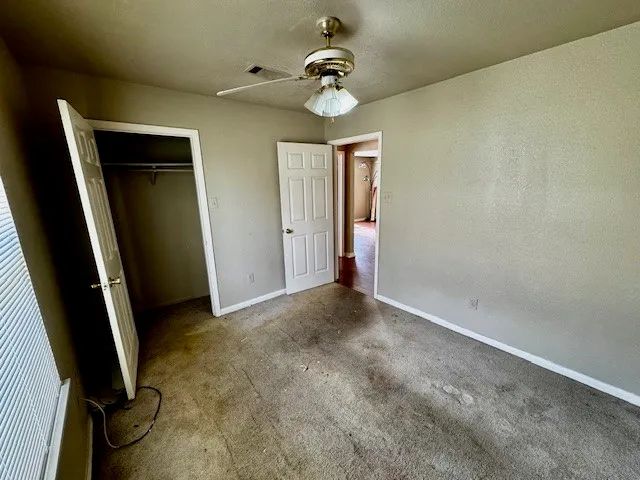 an empty room with a chandelier fan and closet