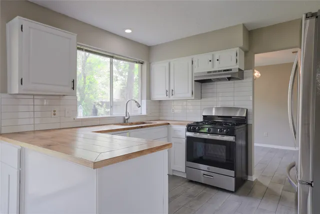 a kitchen with stainless steel appliances granite countertop a stove a refrigerator and a sink with wooden cabinets