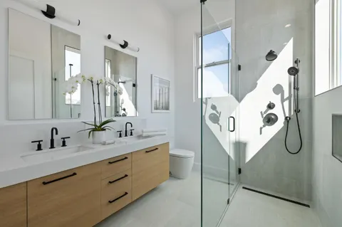 a bathroom with a double vanity sink mirror and shower
