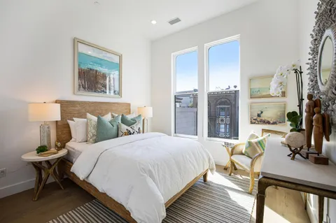 a bedroom with a bed a table and a painting on the wall
