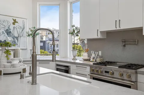 a kitchen with stainless steel appliances a stove and white cabinets