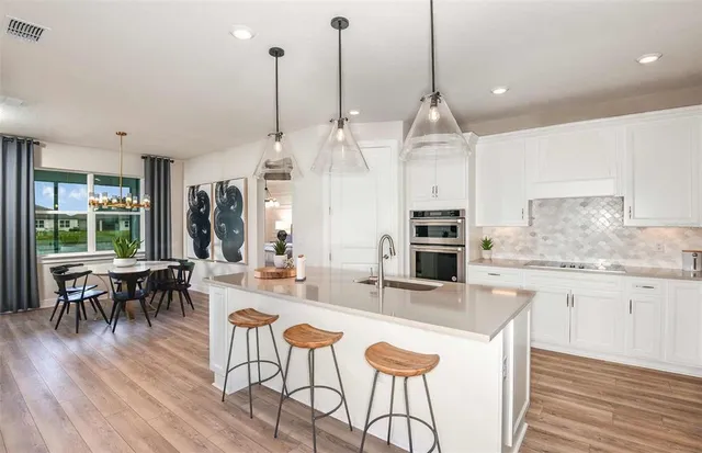 a kitchen with stainless steel appliances kitchen island granite countertop a kitchen island hardwood floor and a view of living room