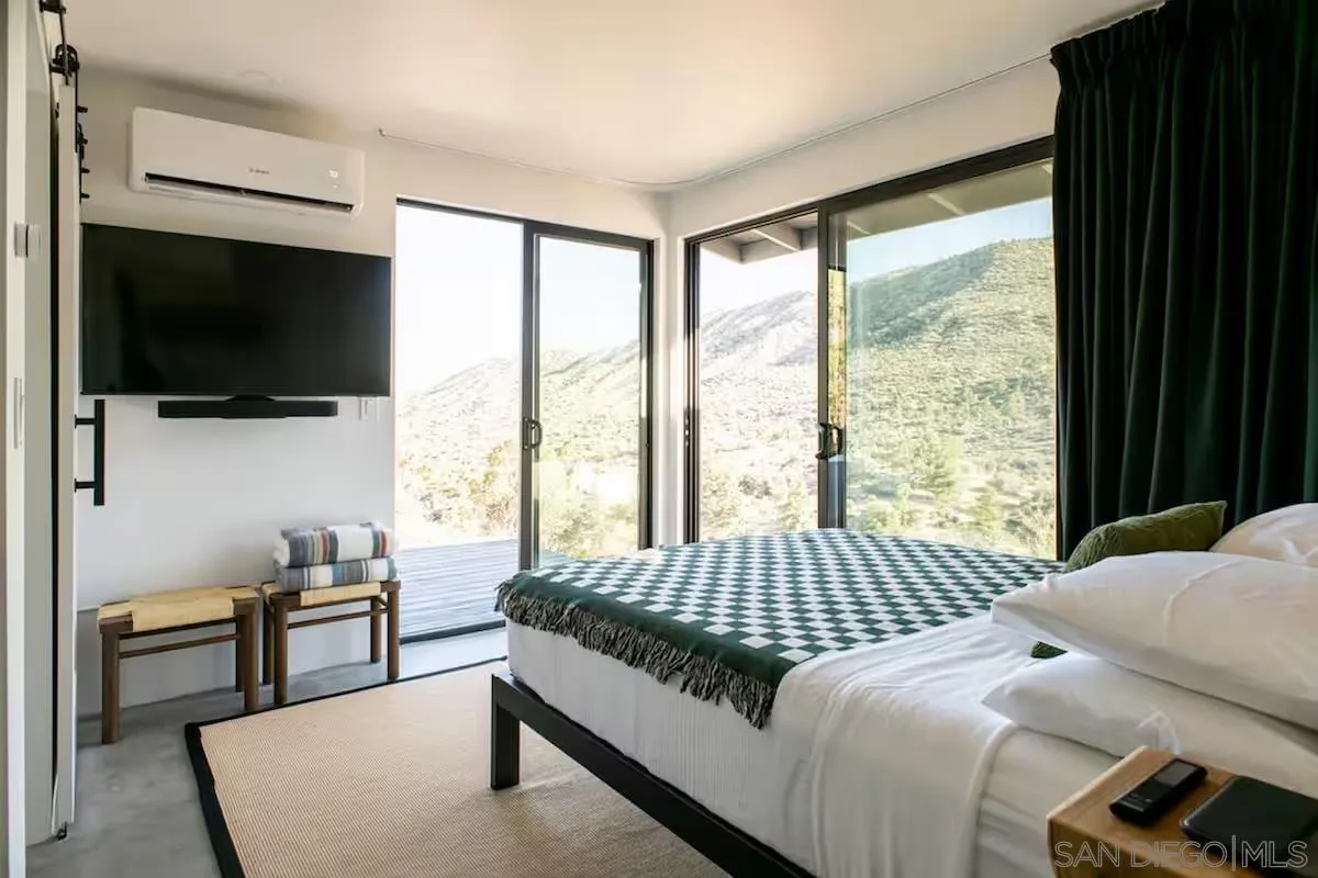 48311 Burns Canyon Road Pioneertown, CA 92268 - Photo 26 of 52 a bedroom with a bed a flat screen tv and a window
