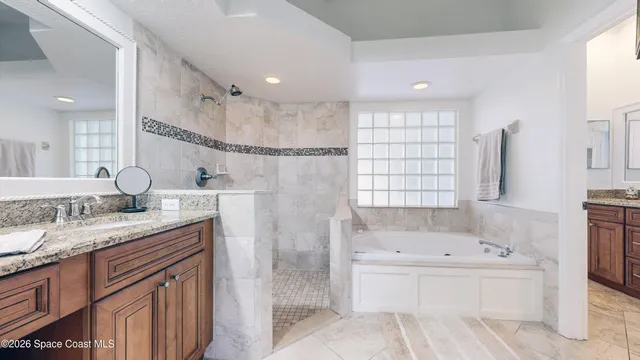 a bathroom with a granite countertop sink mirror and a bathtub