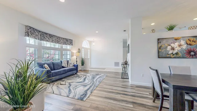 a living room with furniture a wooden floor and a potted plant