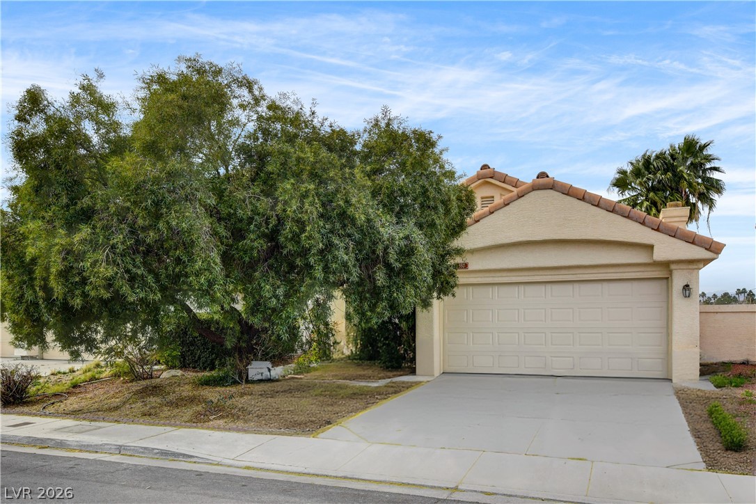 View of front of property with concrete driveway, stucco siding, and an attached garage