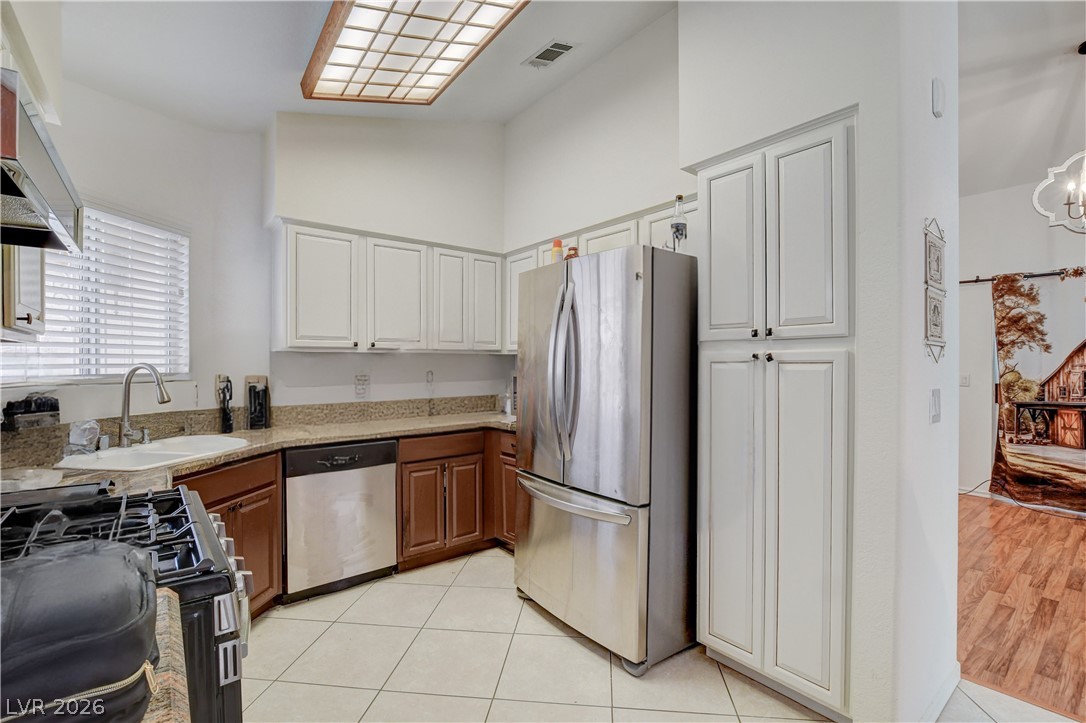 337 Washoe Way Henderson, NV 89074 - Photo 10 of 20 Kitchen with stainless steel appliances, vaulted ceiling, light tile patterned floors, dual tone cabinetry, and a chandelier