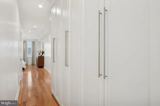 a view of a hallway with wooden floor and a bathroom