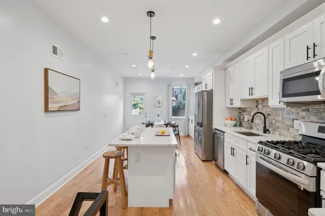 a kitchen with stainless steel appliances a stove a sink a refrigerator cabinets and dining table