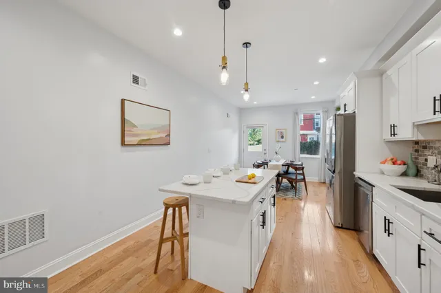 a kitchen with stainless steel appliances kitchen island granite countertop a refrigerator a stove a sink dishwasher and a dining table with wooden floor