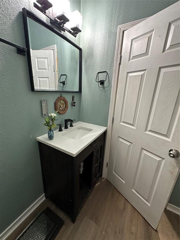 1824 Lyle Avenue Waco, TX 76708 - Photo 11 of 13 Bathroom featuring a textured wall, dark wood-style flooring, and vanity